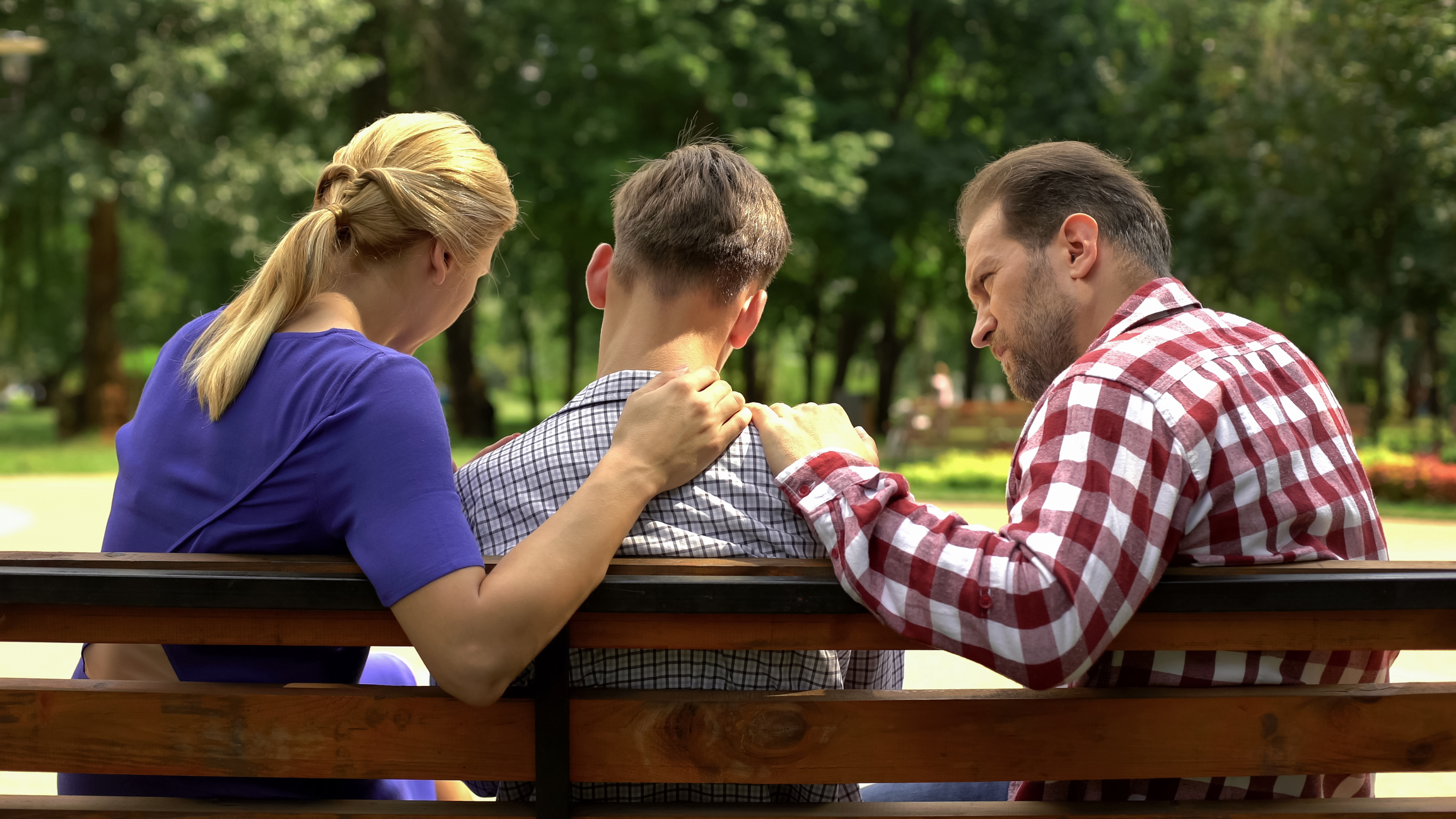 concerned family parents on park bench talking to young adult