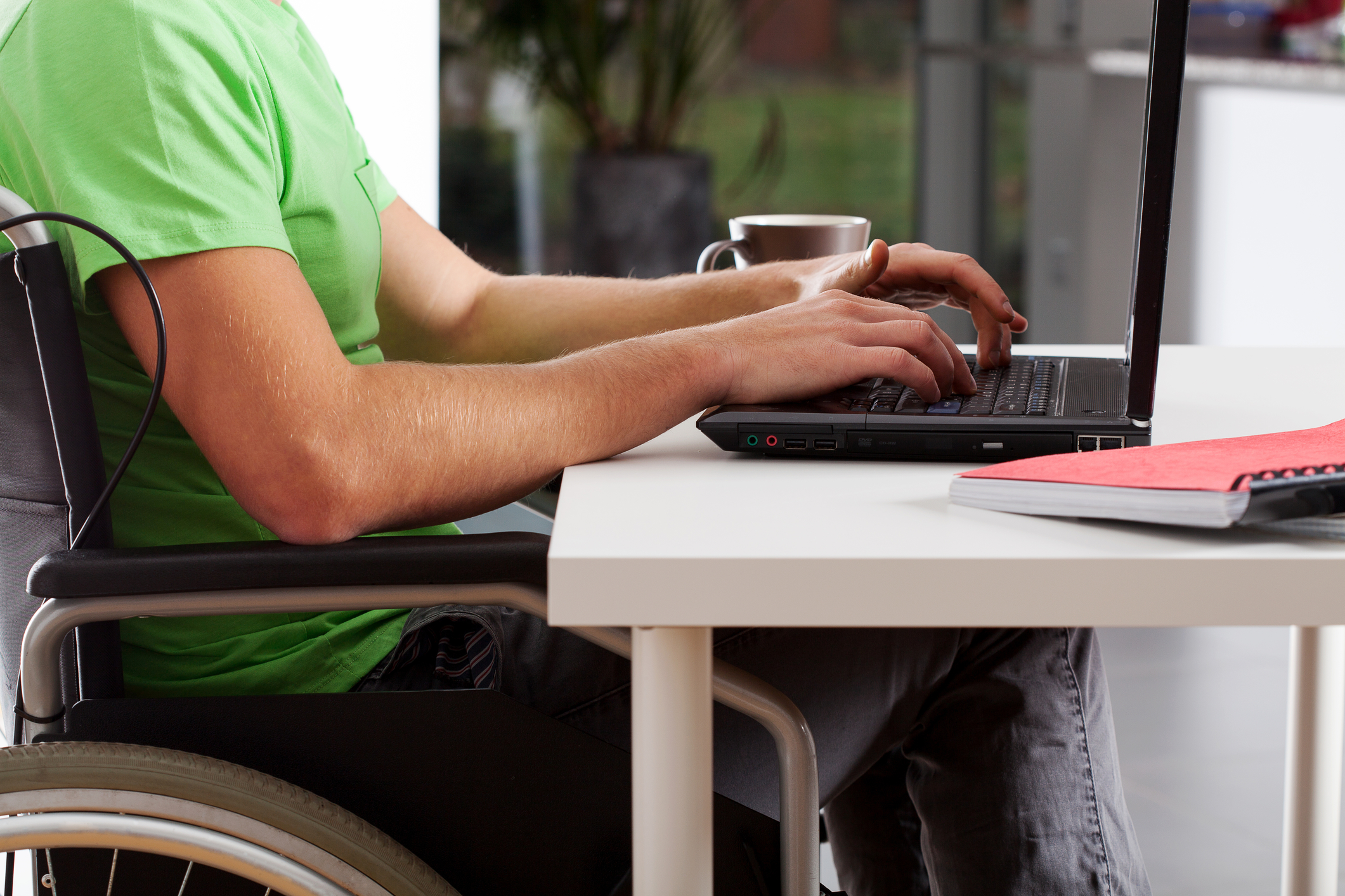 person in wheelchair typing on laptop